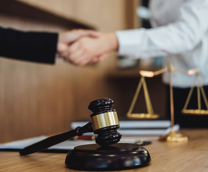 Gavel on desk while two people shake hands